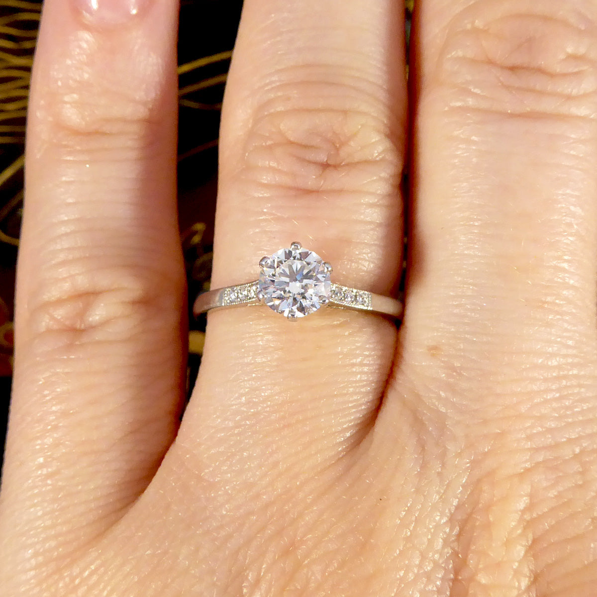 Close-up of a hand wearing a diamond ring with a blurred background