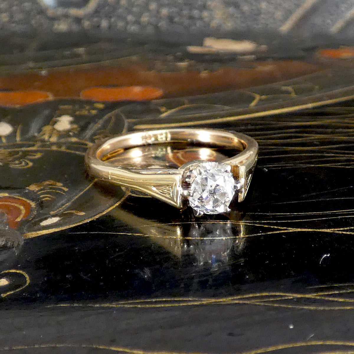 Gold ring with a diamond on a decorative black surface