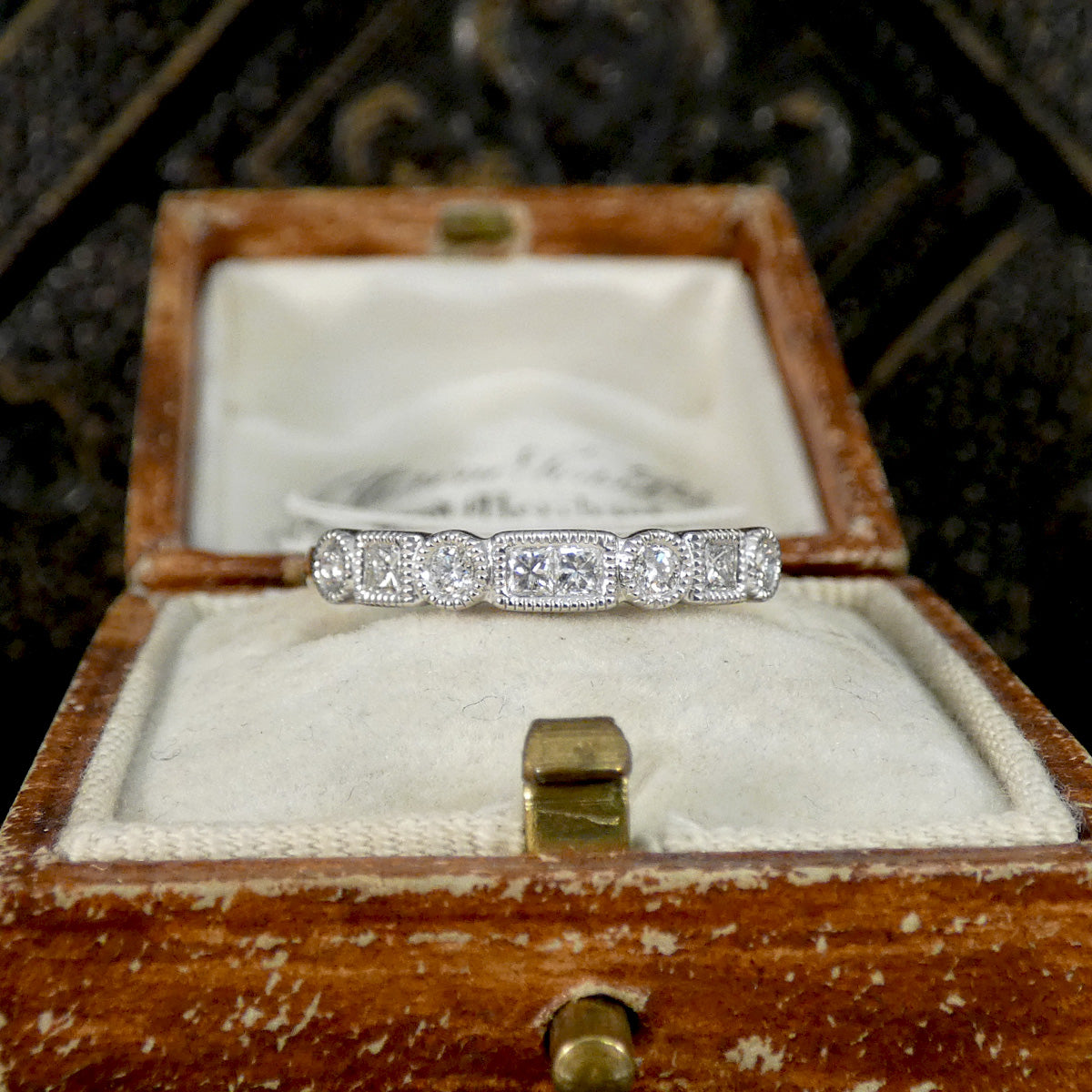 Diamond ring in a wooden box with a decorative background