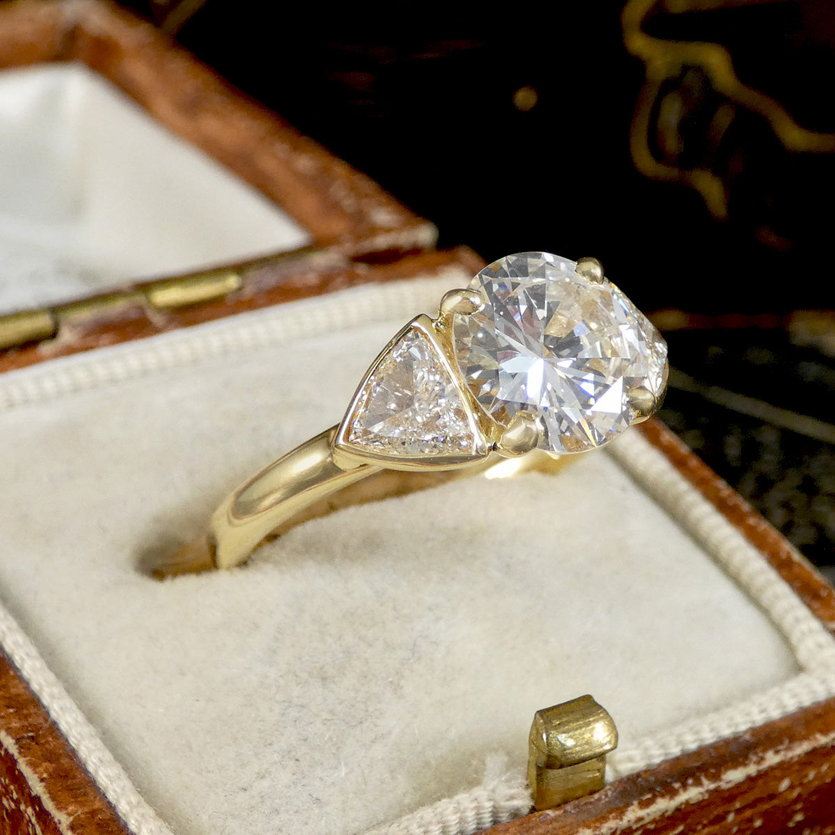 Gold ring with three diamonds in a wooden box