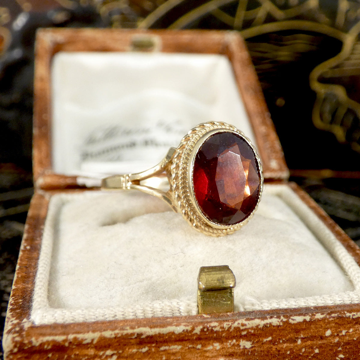 Gold ring with a red gemstone in an open wooden box