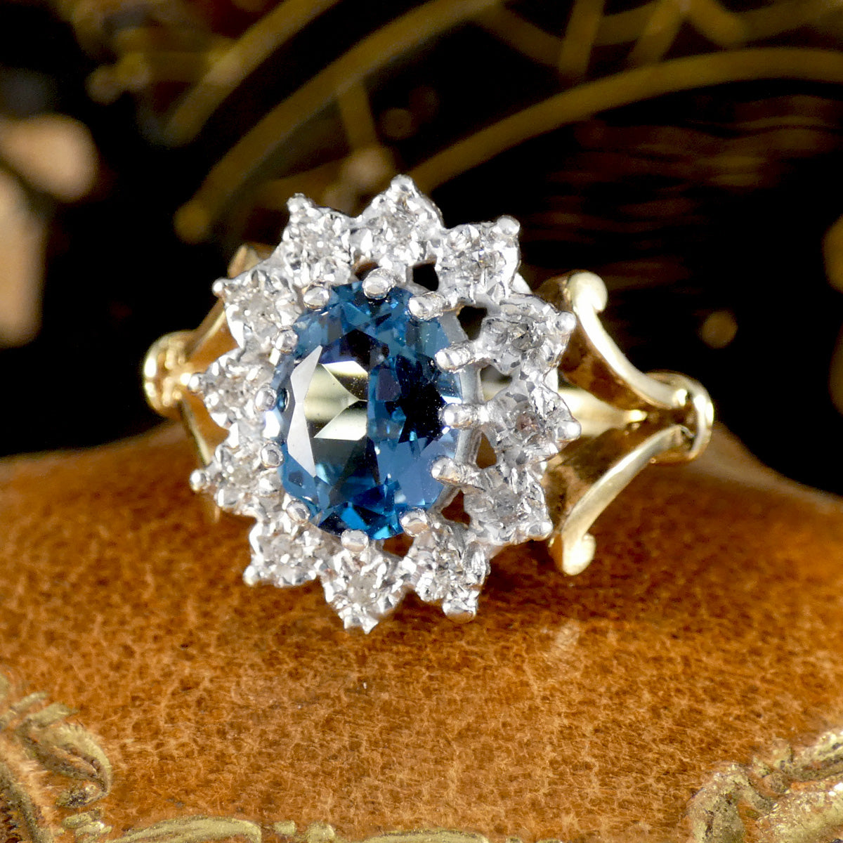 Gold ring with a blue gemstone and diamond accents on a textured surface