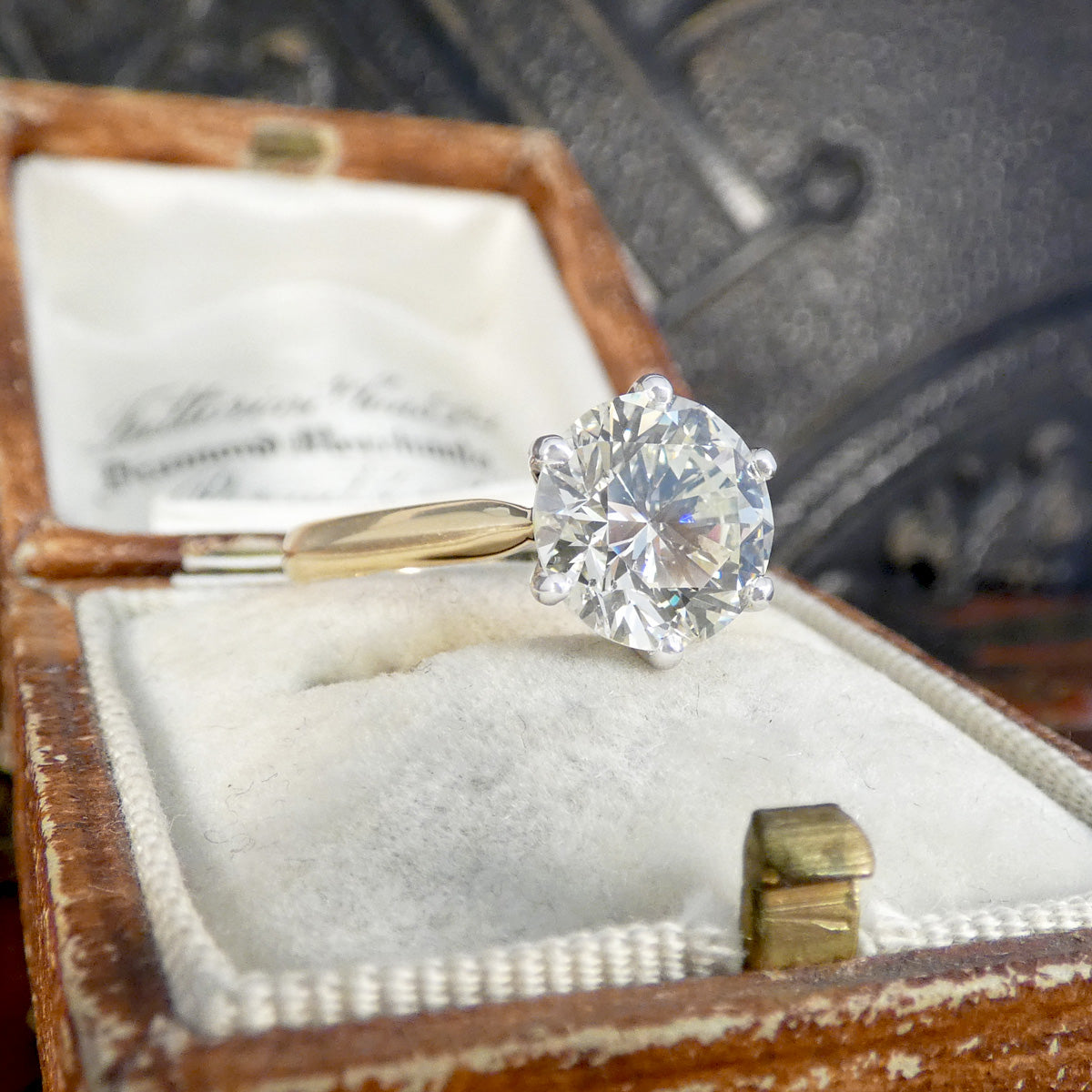 Diamond ring in a wooden box with a vintage car in the background