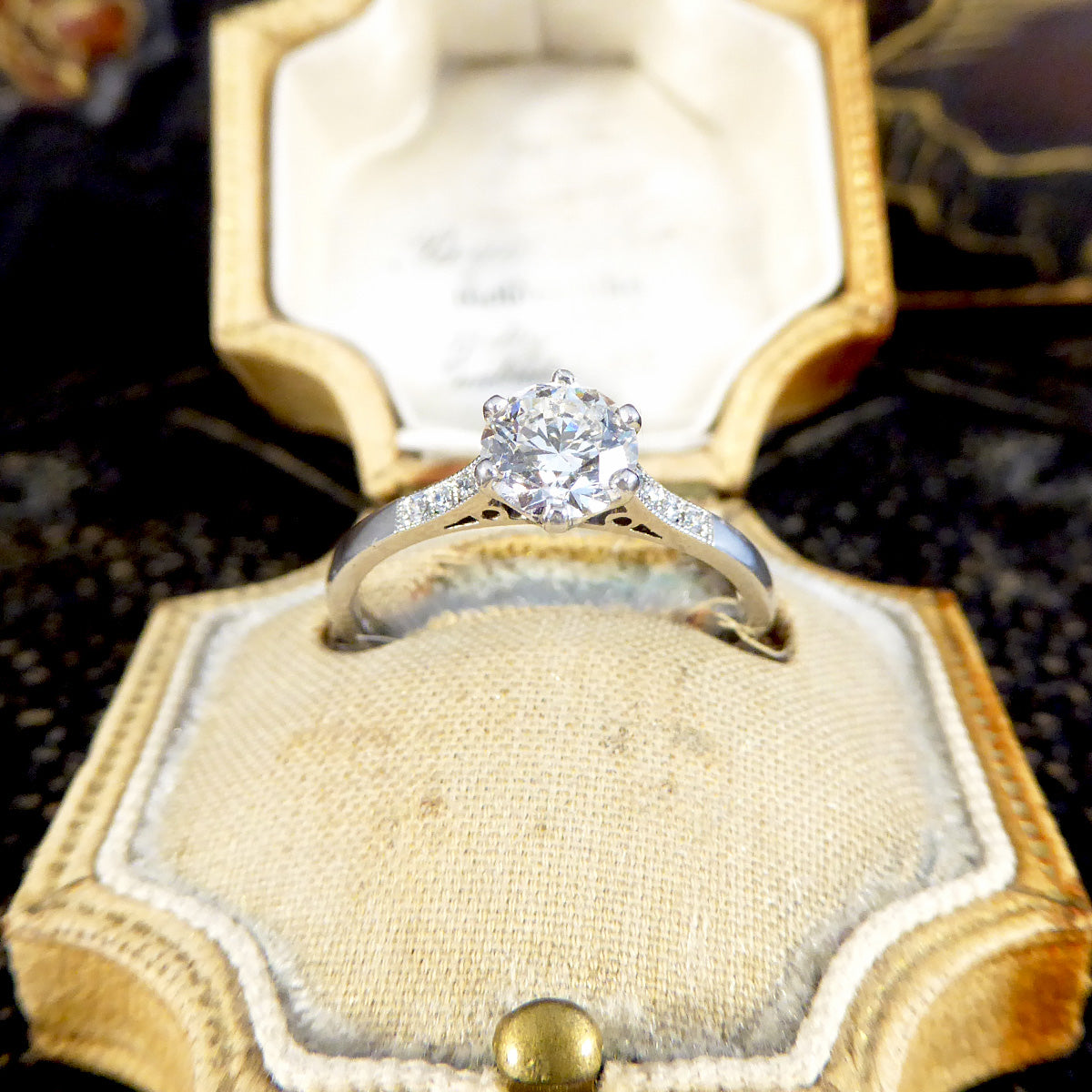 Diamond ring in a gold box on a textured surface