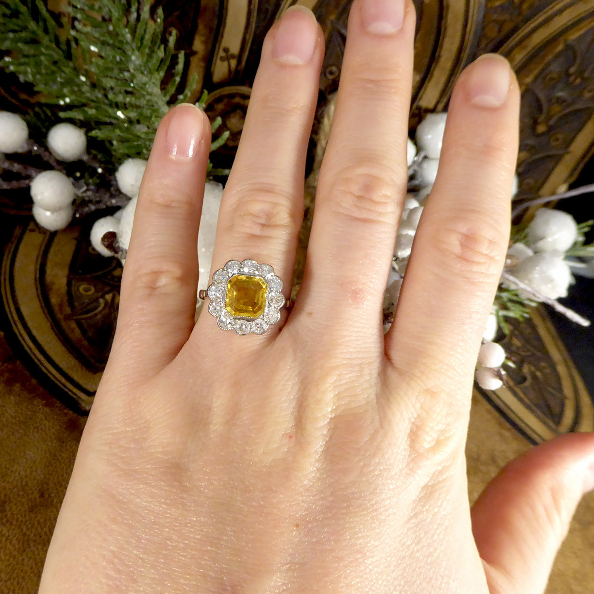 Art Deco-style Asscher cut yellow sapphire and diamond cluster ring showcased on a hand, highlighting the intricate design and elegant setting.