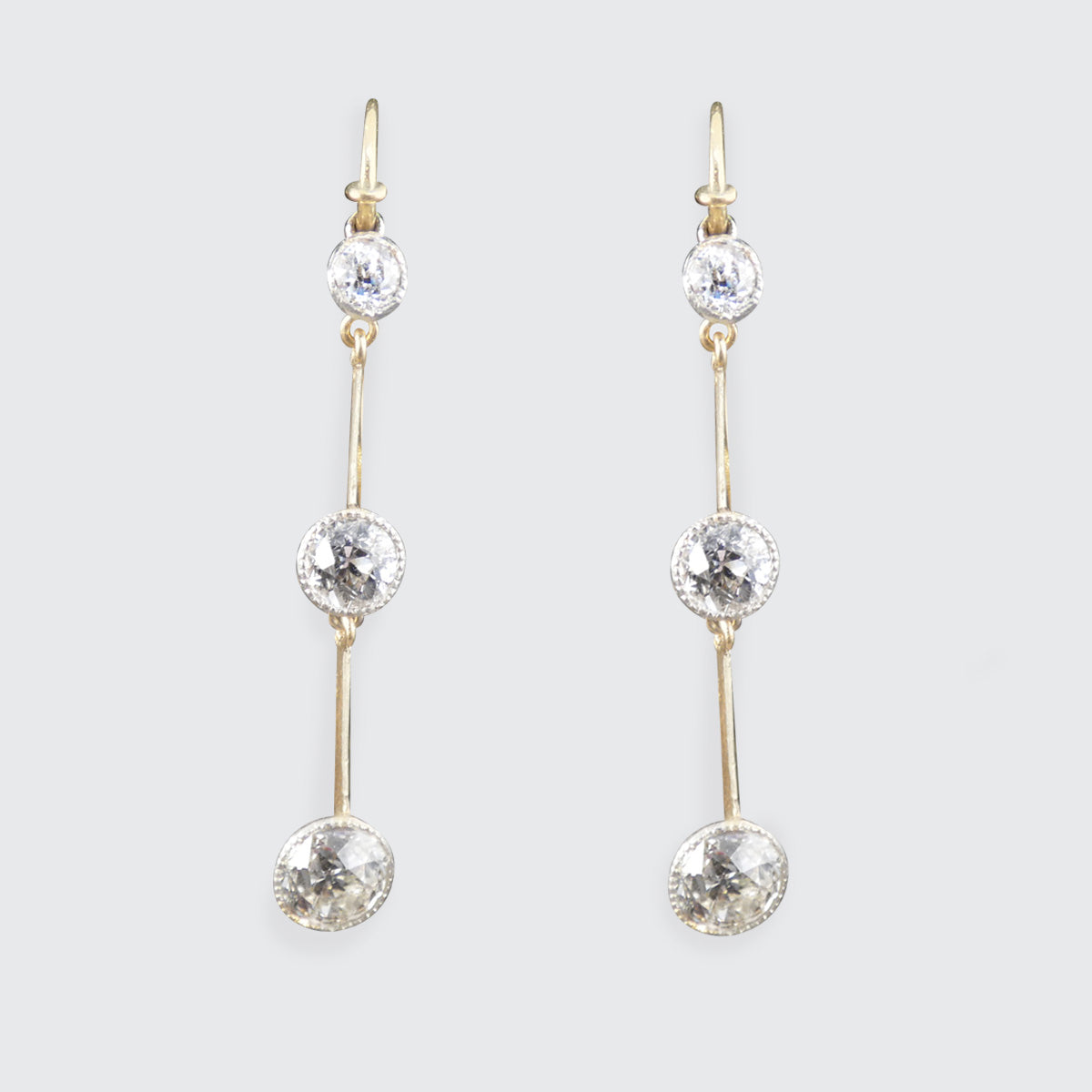 Pair of antique gold and diamond drop earrings on a light gray background