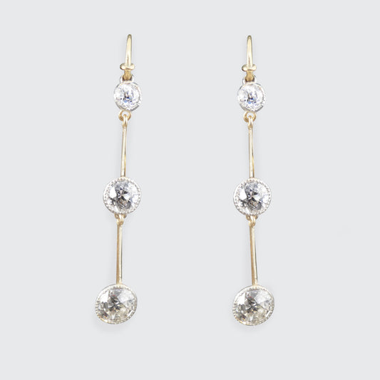 Pair of antique gold and diamond drop earrings on a light gray background