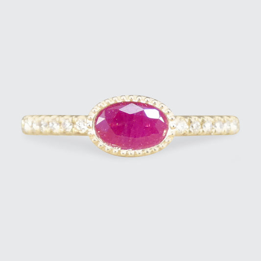 Gold ring with a pink ruby gemstone on a light gray background