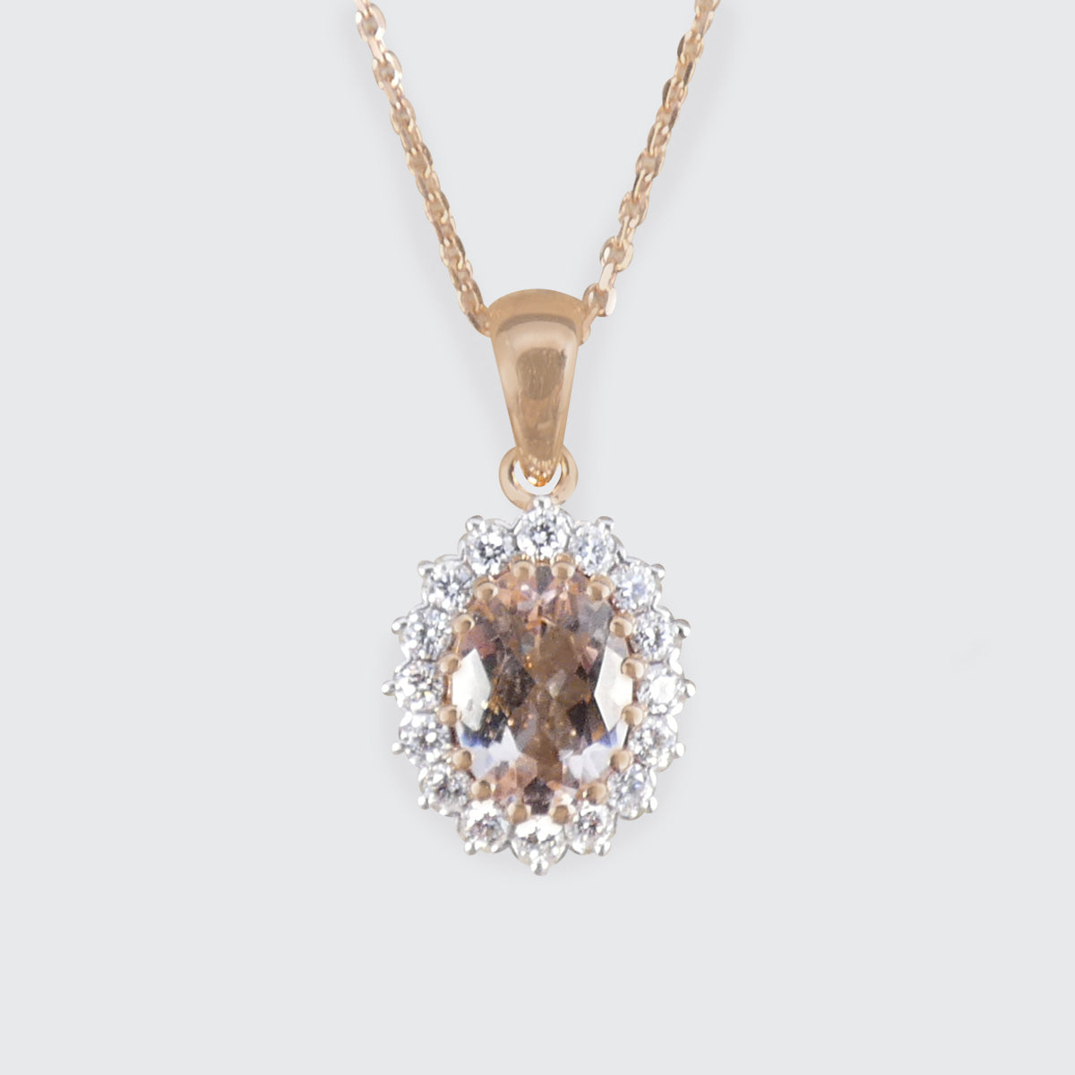 Gold necklace with a pendant featuring a pink gemstone and clear diamonds on a light gray background