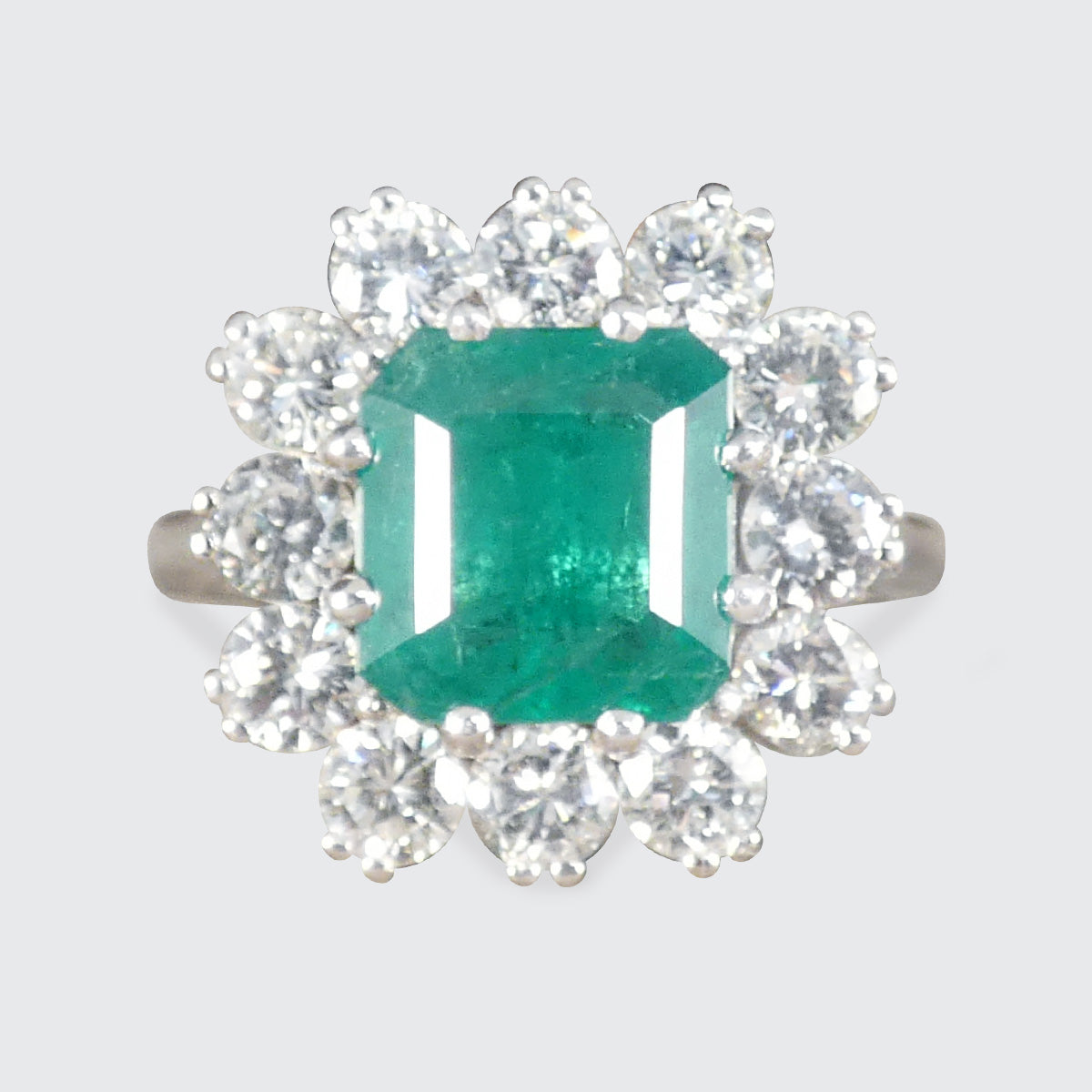 A gorgeous Emerald and Diamond cluster ring in 18ct white gold and platinum showing a gorgeous and bright emerald colour.