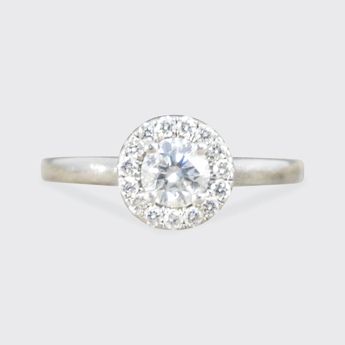 Diamond ring with a halo on a light gray background