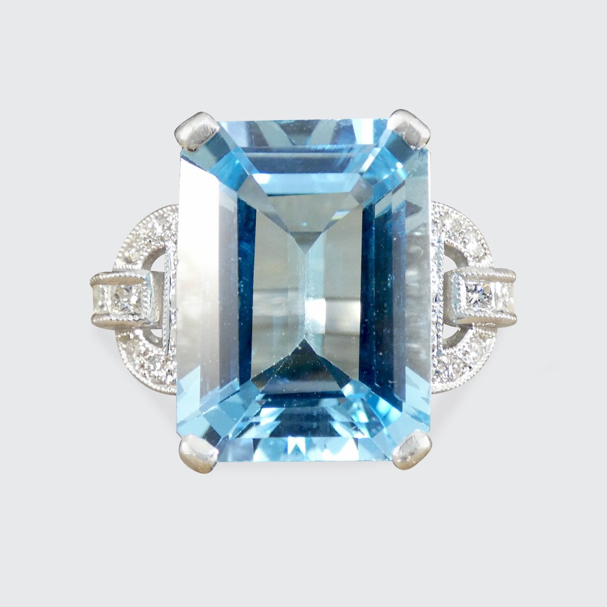 Ring with a large blue gemstone and smaller diamonds on a light gray background
