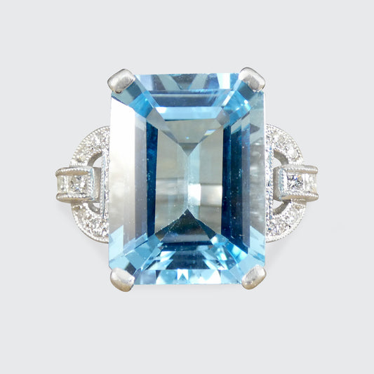 Ring with a large blue gemstone and smaller diamonds on a light gray background