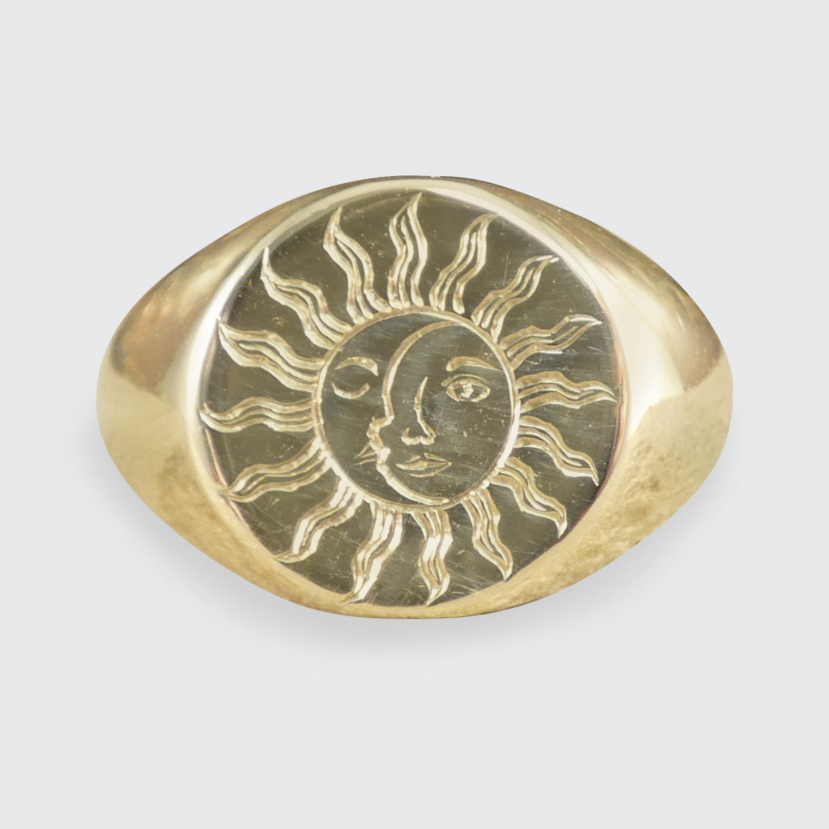 A solid yellow gold signet ring with a face engraved with a sun and moon