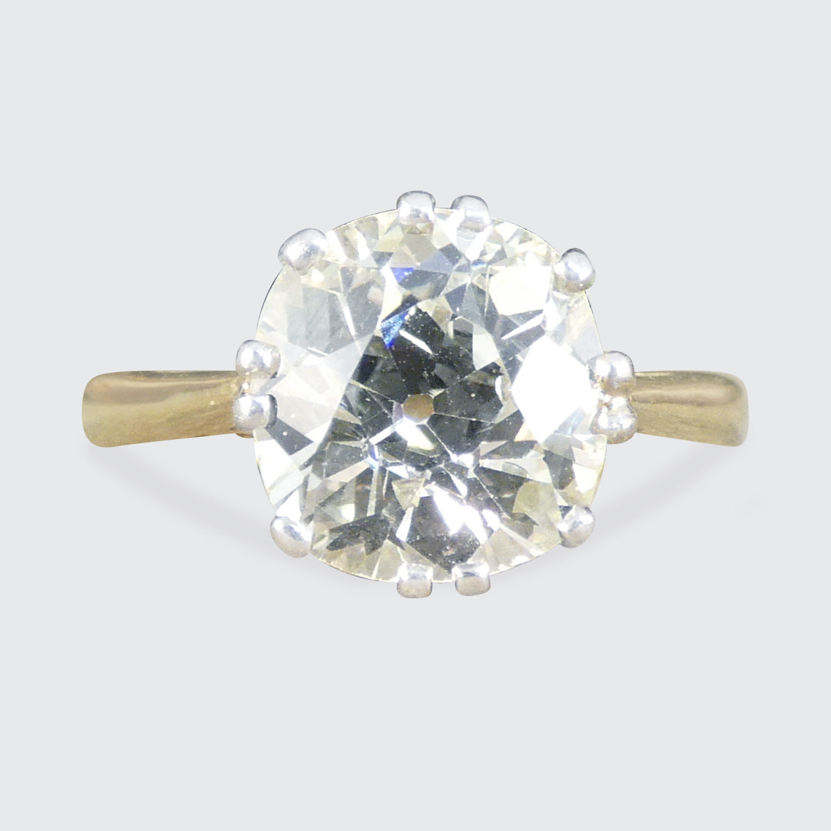 Gold ring with a large diamond on a light gray background