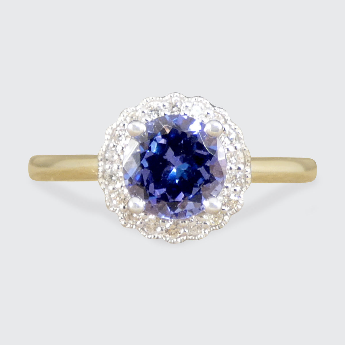 Ring with a blue gemstone and diamond halo on a light gray background