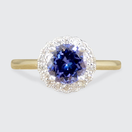 Ring with a blue gemstone and diamond halo on a light gray background