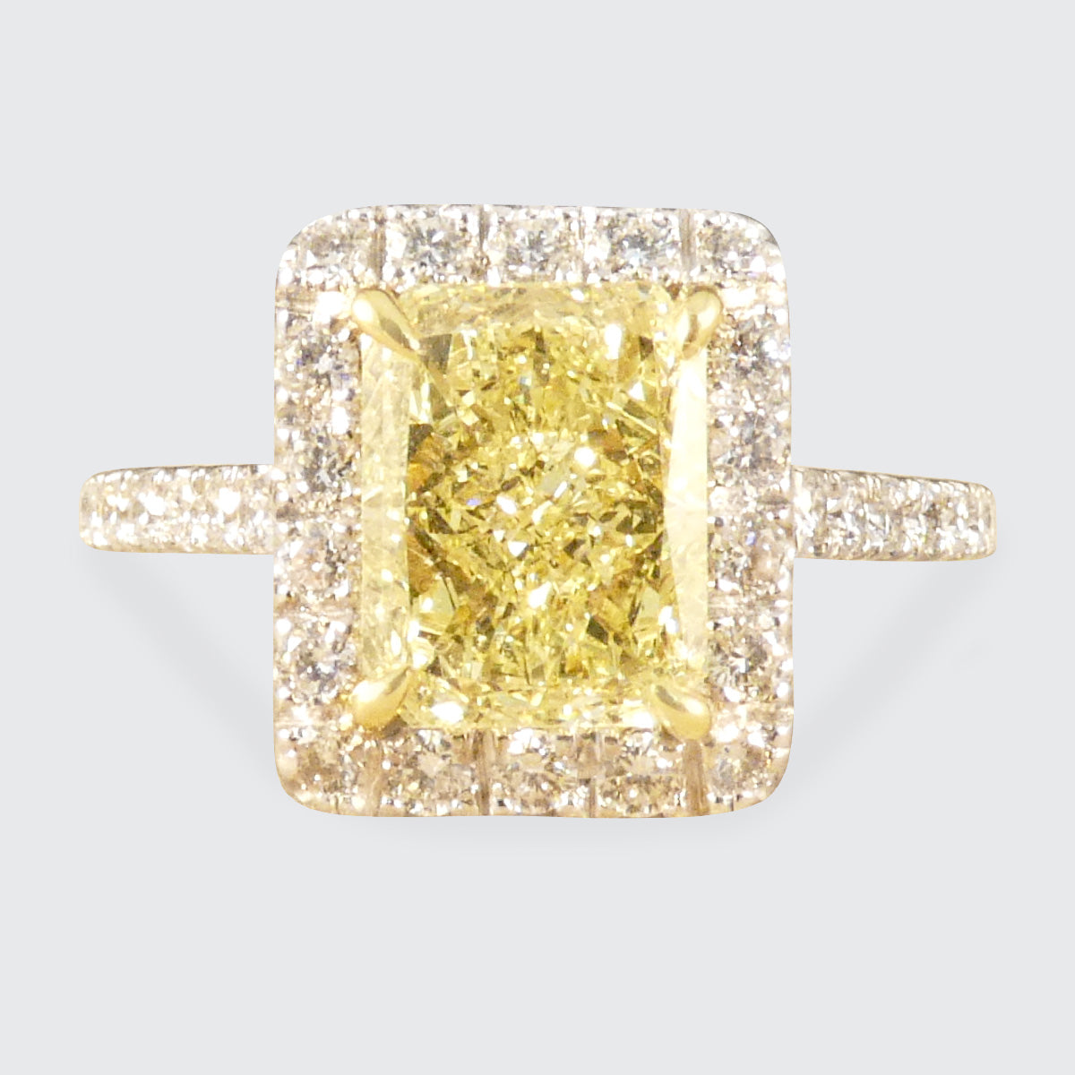 Natural Yellow Radiant Cut Diamond with GIA grading in a four claw setting. Surrounded by a halo of bright white Diamonds and Diamond set shoulders in 18ct White Gold.