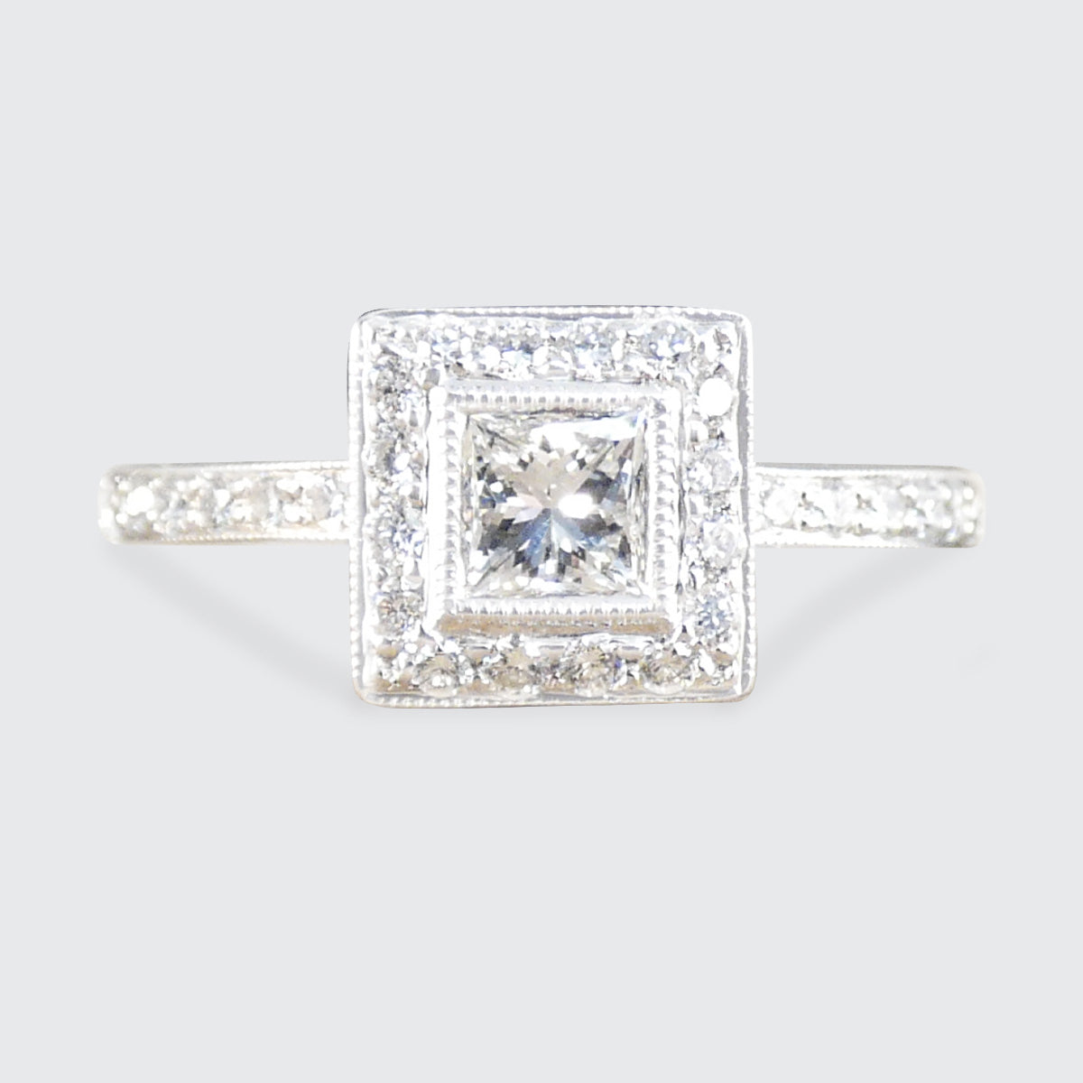 Diamond ring with a square halo on a light gray background