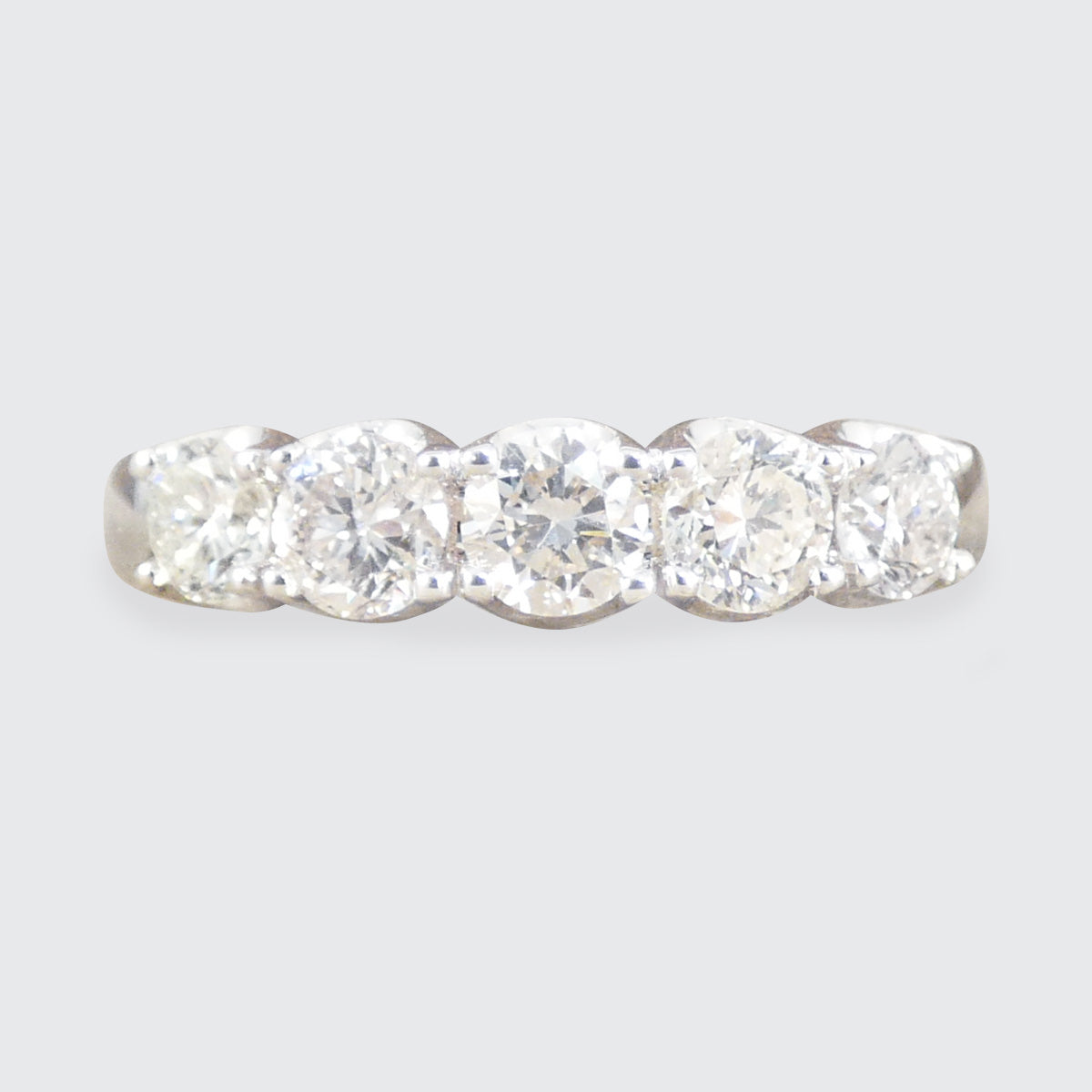 Diamond ring with five clear stones on a light gray background