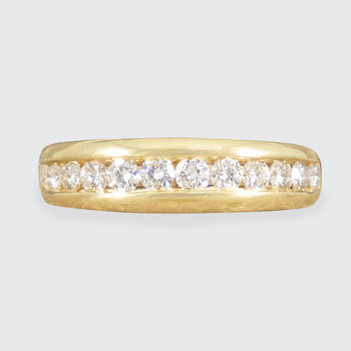 Gold ring with diamonds on a light gray background