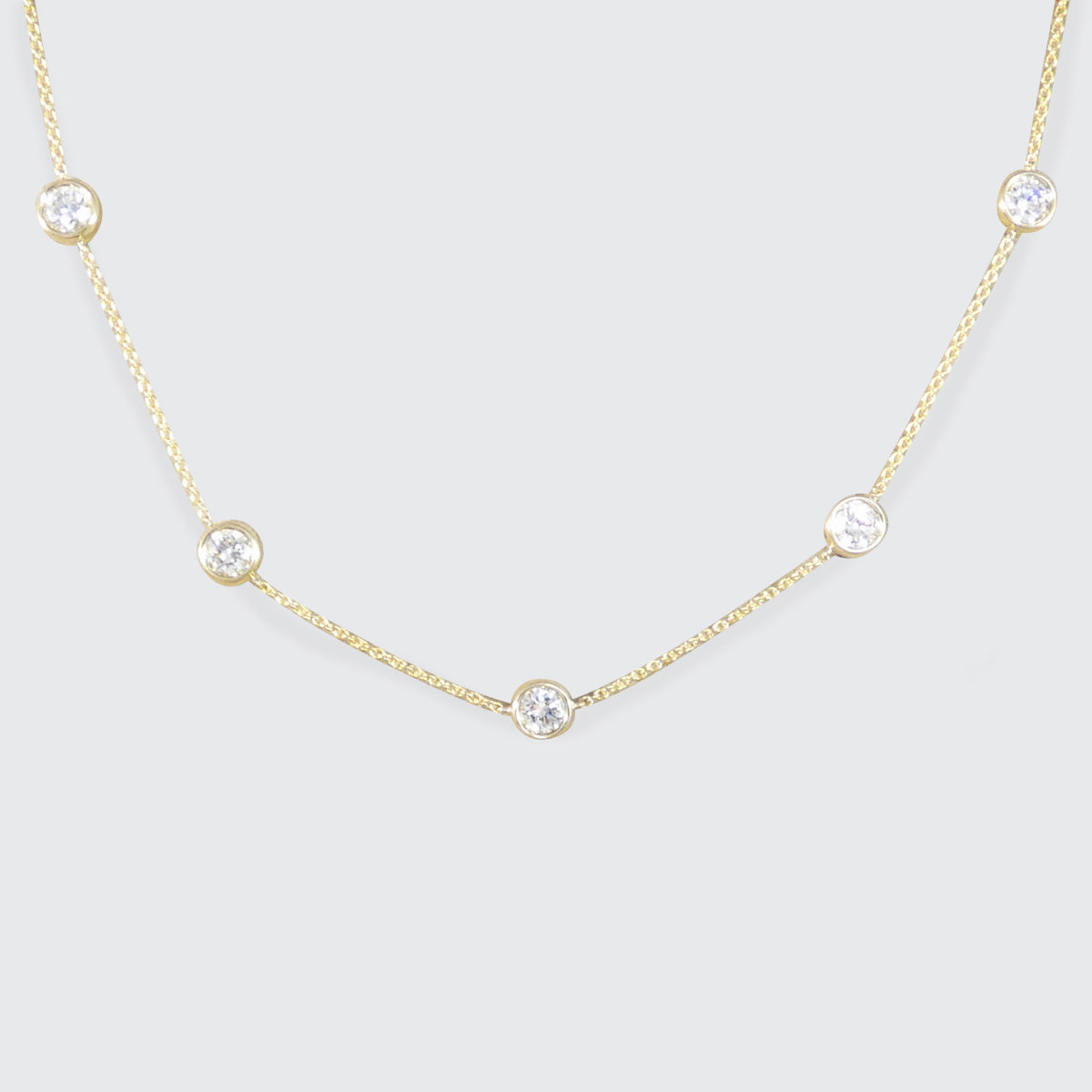 Diamond station necklace with bezel set diamonds on a gold chain necklace.
