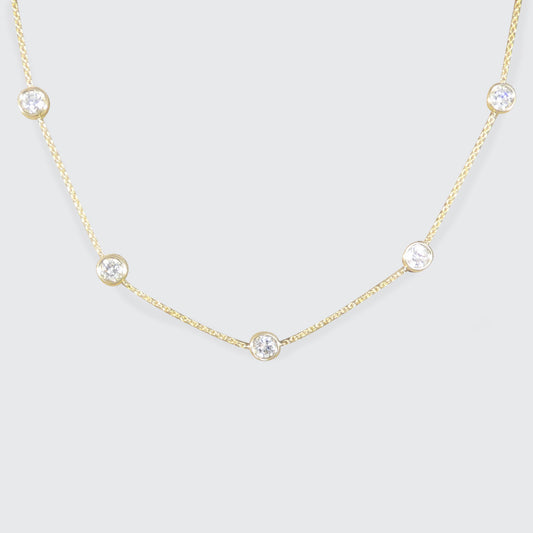 Diamond station necklace with bezel set diamonds on a gold chain necklace.