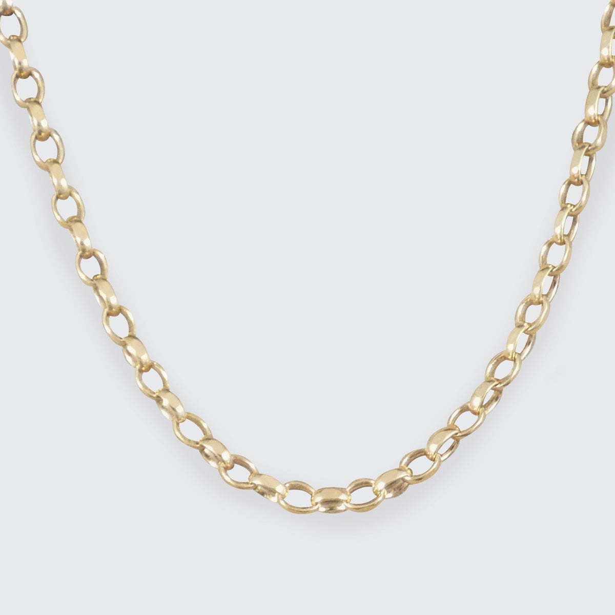 A close-up of a gold chain necklace with elongated oval links, shown against a light gray background.