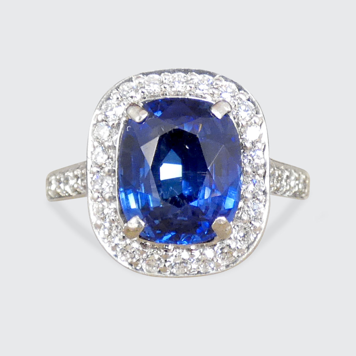 A sapphire and diamond cluster ring with a diamond set shoulder and wedfit appearences.