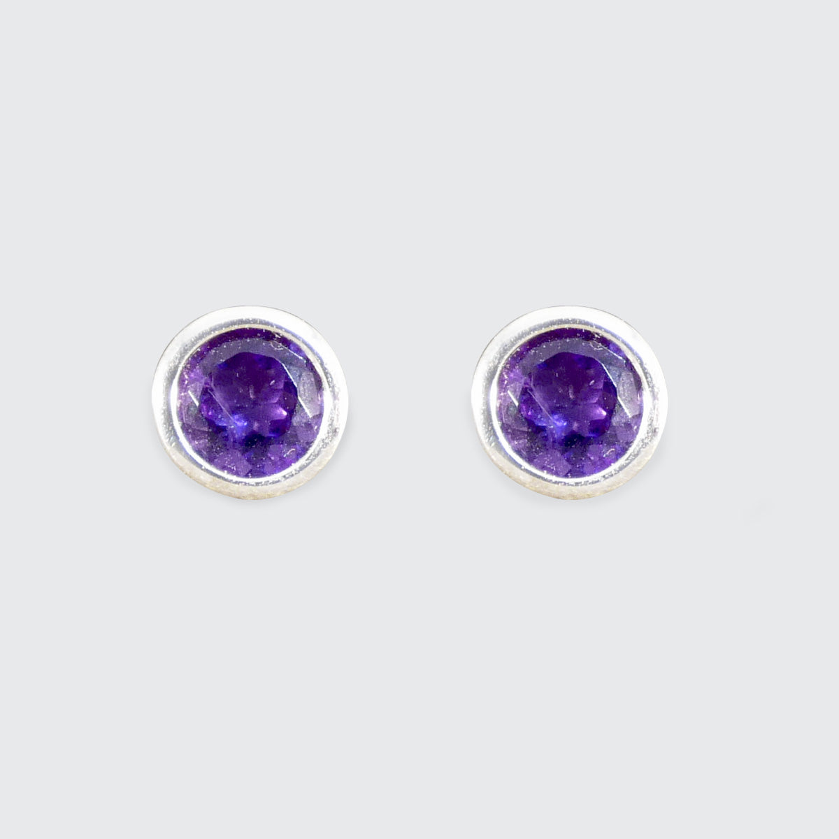 Pair of round purple gemstone stud earrings on a light gray background