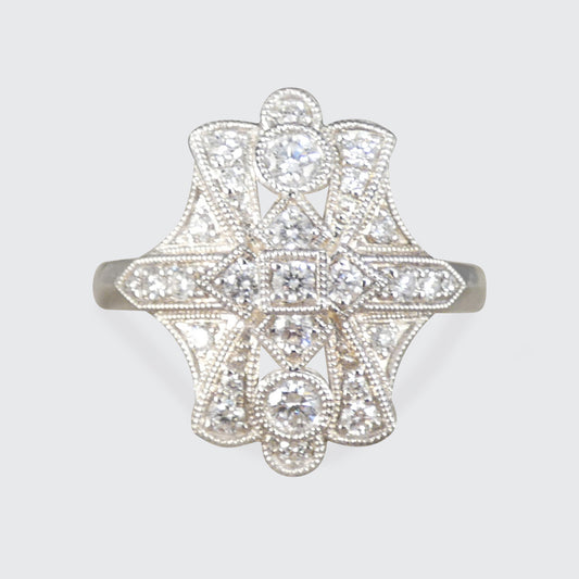 An ornate Art Deco style diamond ring featuring a symmetrical starburst design with multiple round and oval diamonds set in a silver-toned metal band, shown against a light gray background.