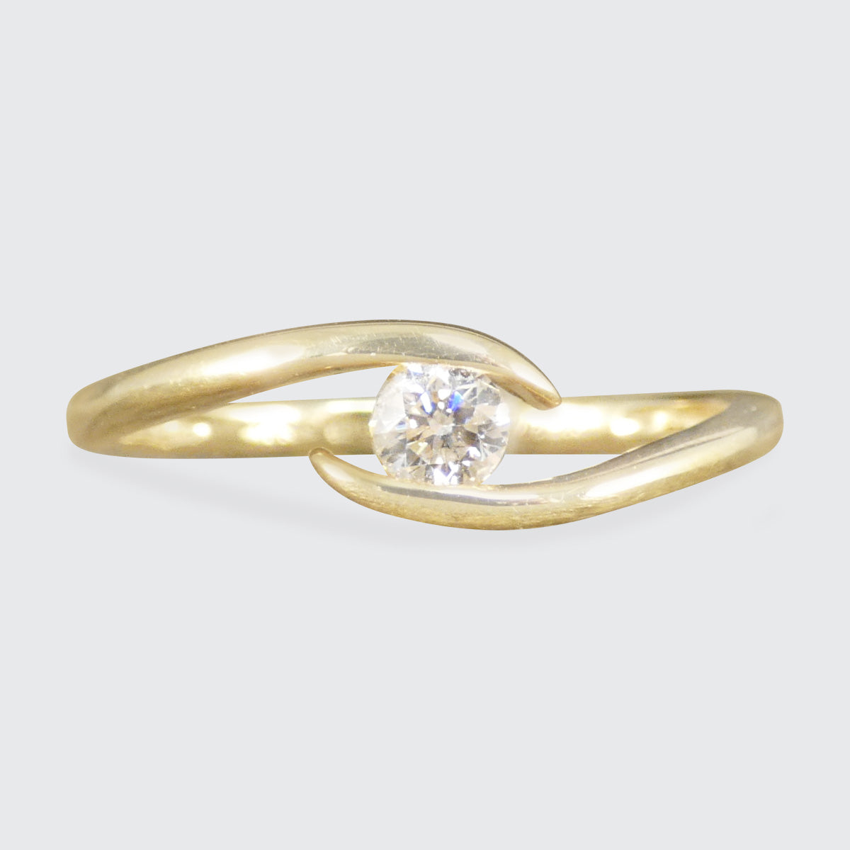 Gold ring with a diamond on a light gray background