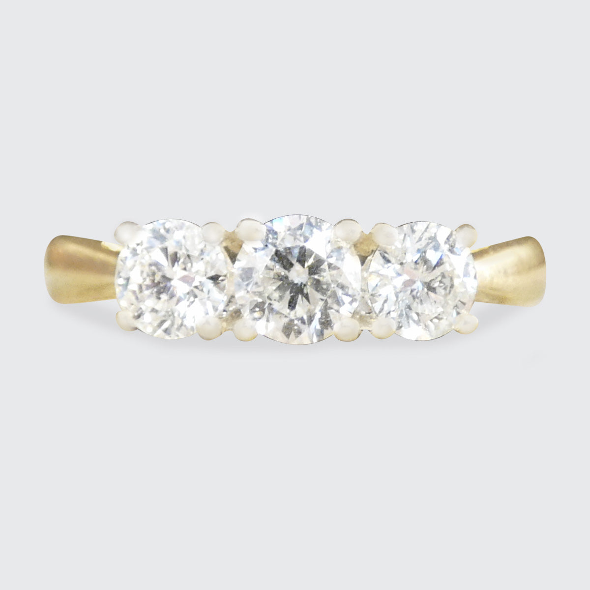 Gold ring with three diamonds on a light gray background