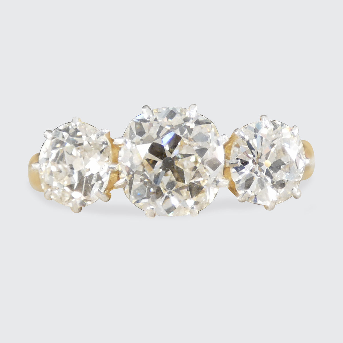 A chunky old cushion cut diamond three stone ring in 18ct yellow gold