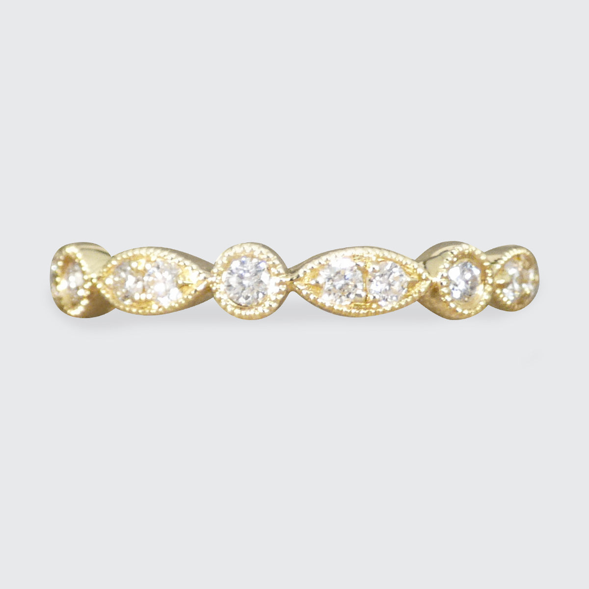 Gold ring with four diamonds on a light gray background