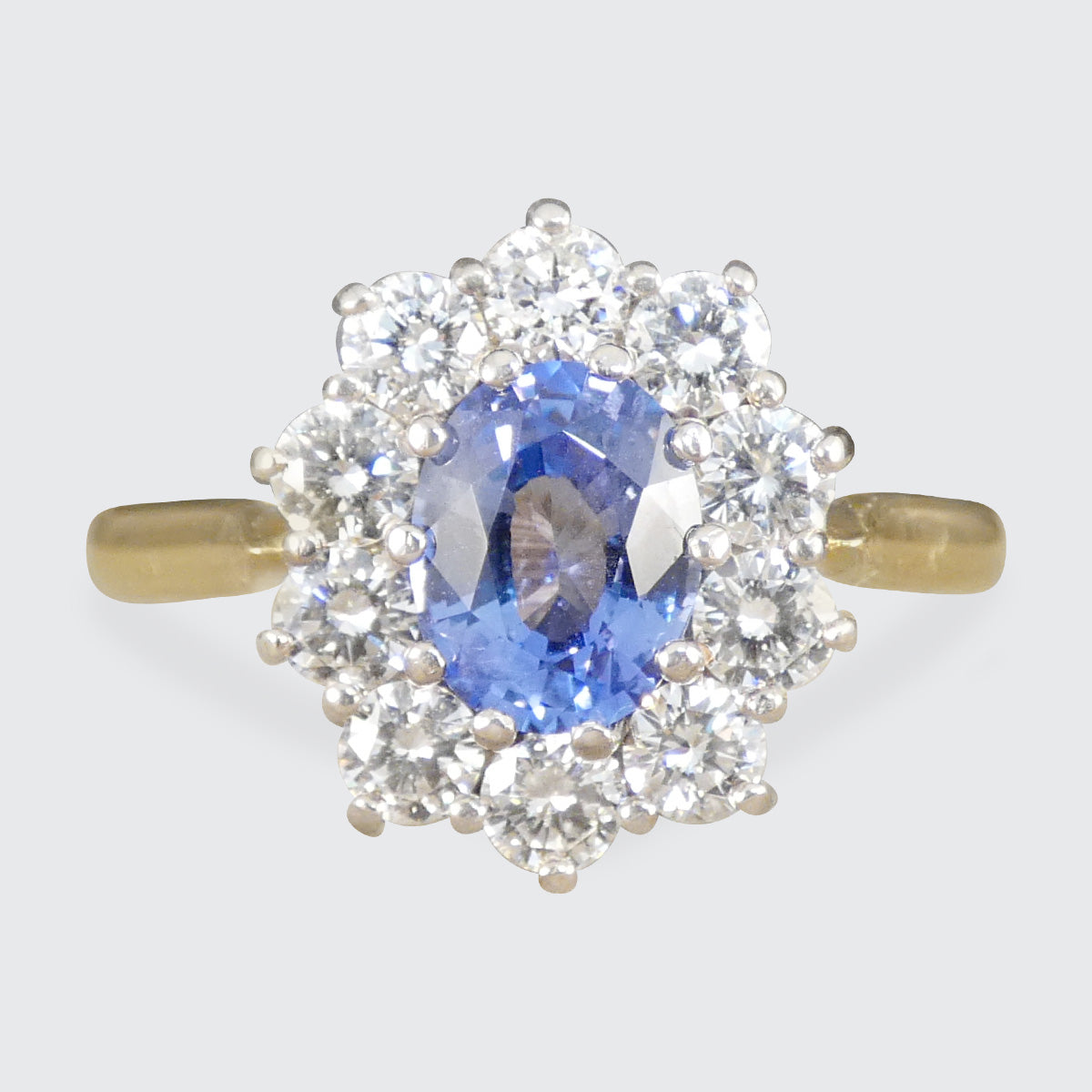 Ring with a blue gemstone and diamond halo on a light gray background