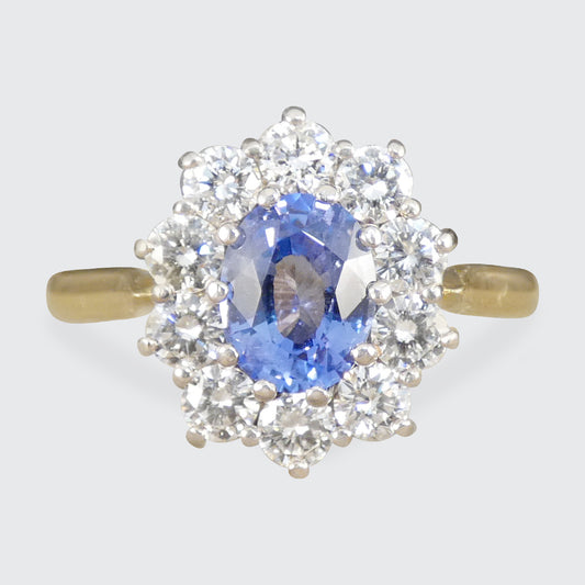 Ring with a blue gemstone and diamond halo on a light gray background