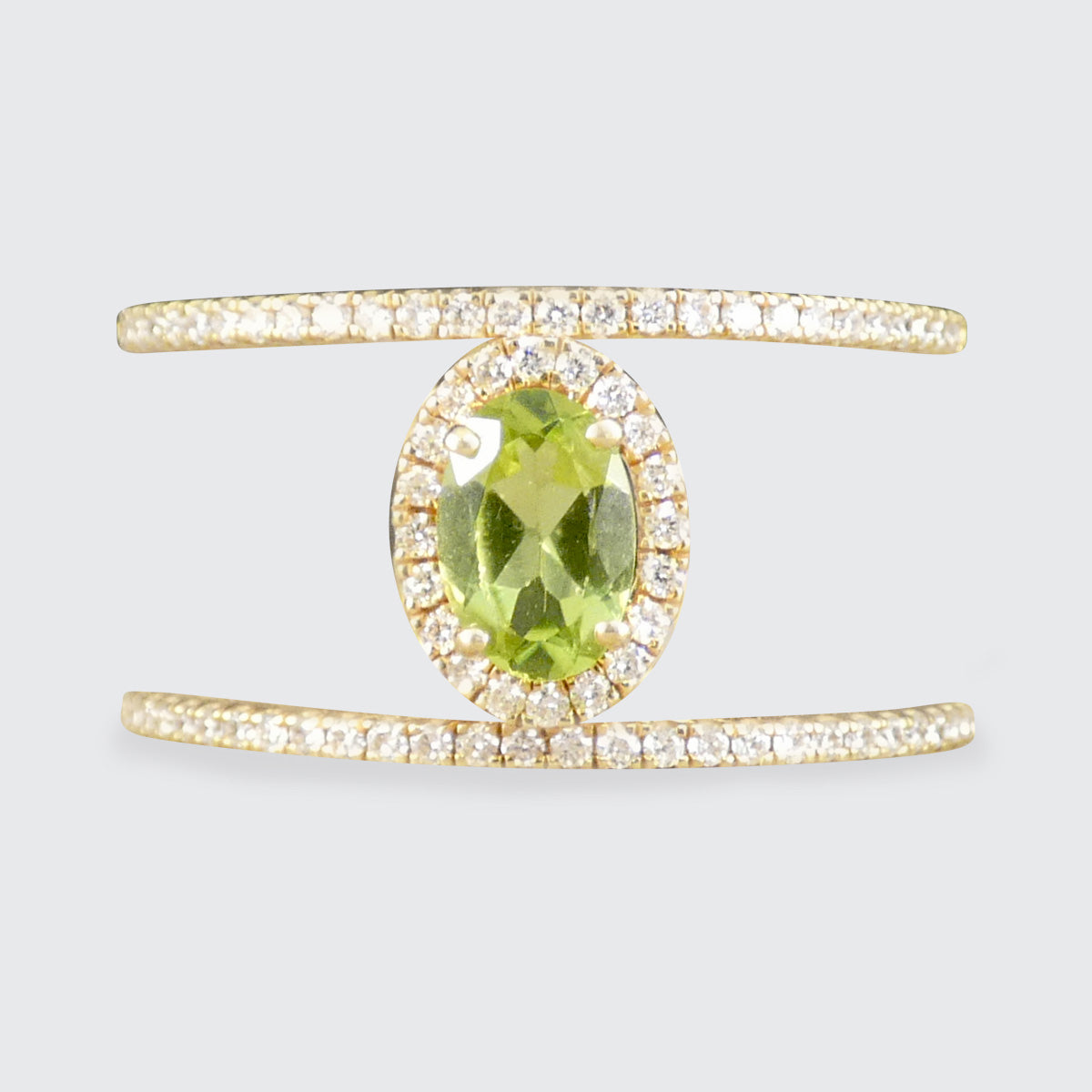 Gold ring with a green gemstone on a light gray background