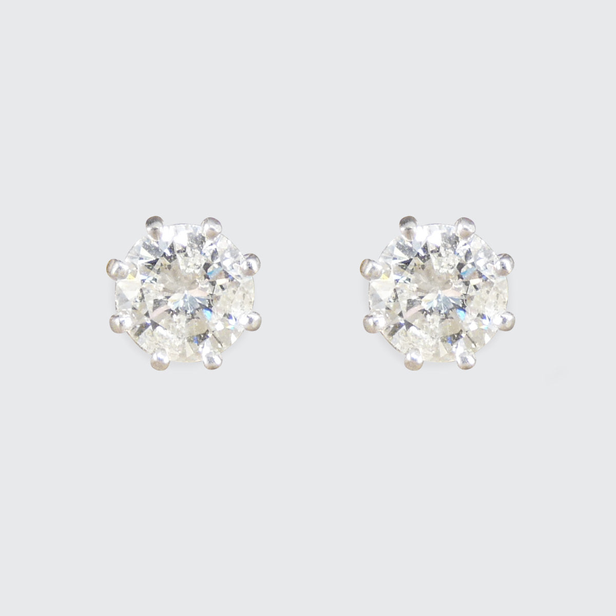 Pair of diamond stud earrings on a light gray background
