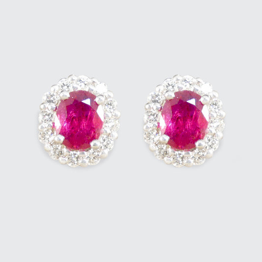 Pair of earrings with pink ruby gemstones and silver surrounds on a light gray background