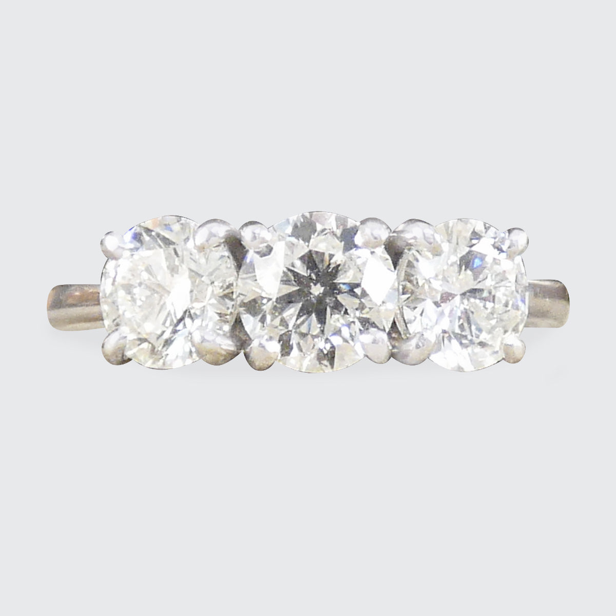 Three-stone diamond ring on a light gray background