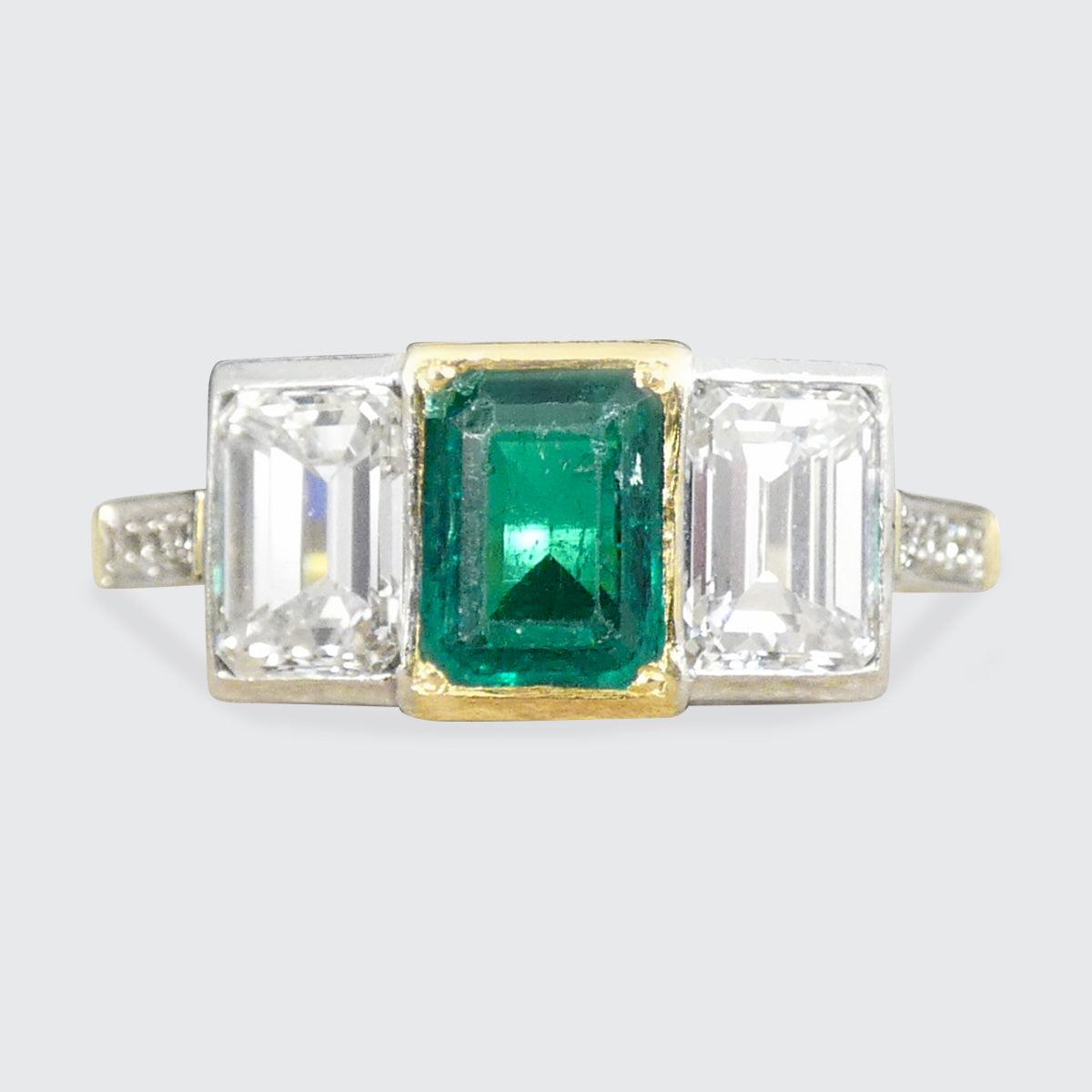 An Emerald and Diamond three stone ring in 18ct white and yellow gold.