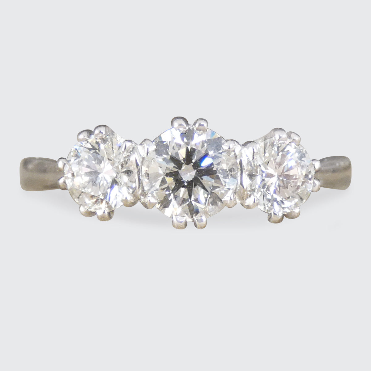 Three-stone diamond ring on a light gray background