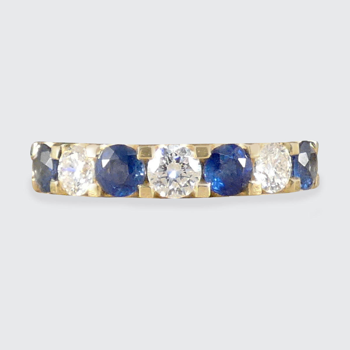 A Sapphire and Diamond half eternity ring in yellow gold.