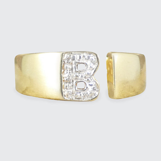 Gold ring with letter 'B' on a light gray background