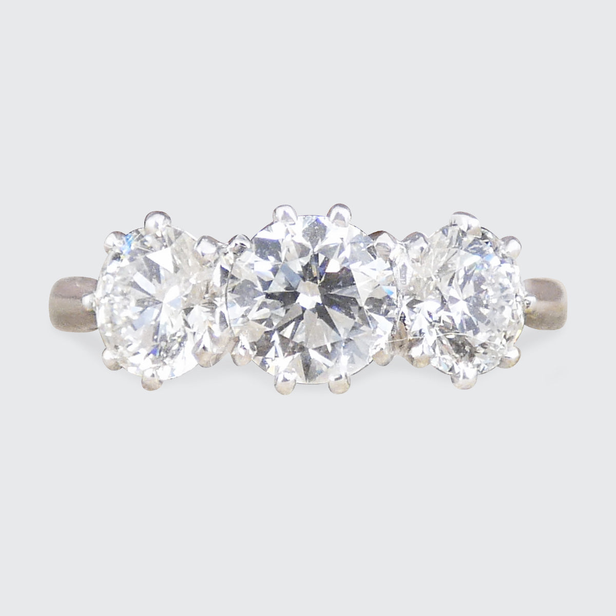 Three-stone diamond ring on a light gray background