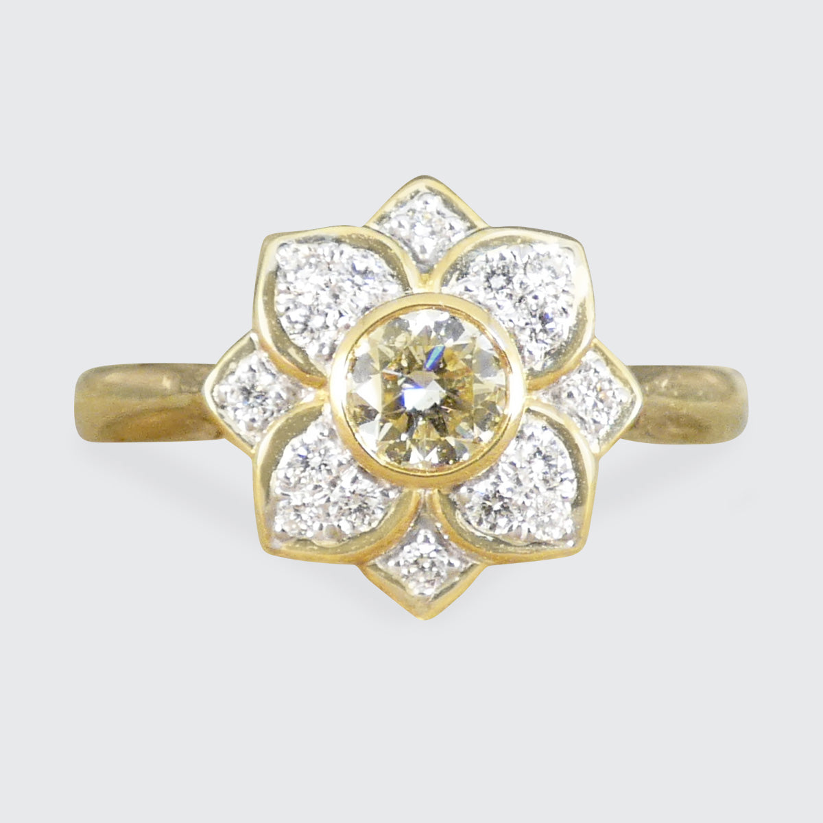 Gold ring with diamond flower design on a light gray background