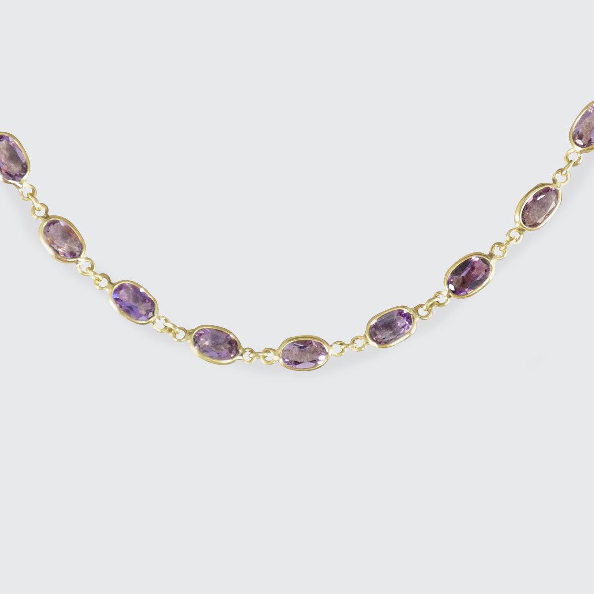 Gold necklace with purple gemstones on a white background