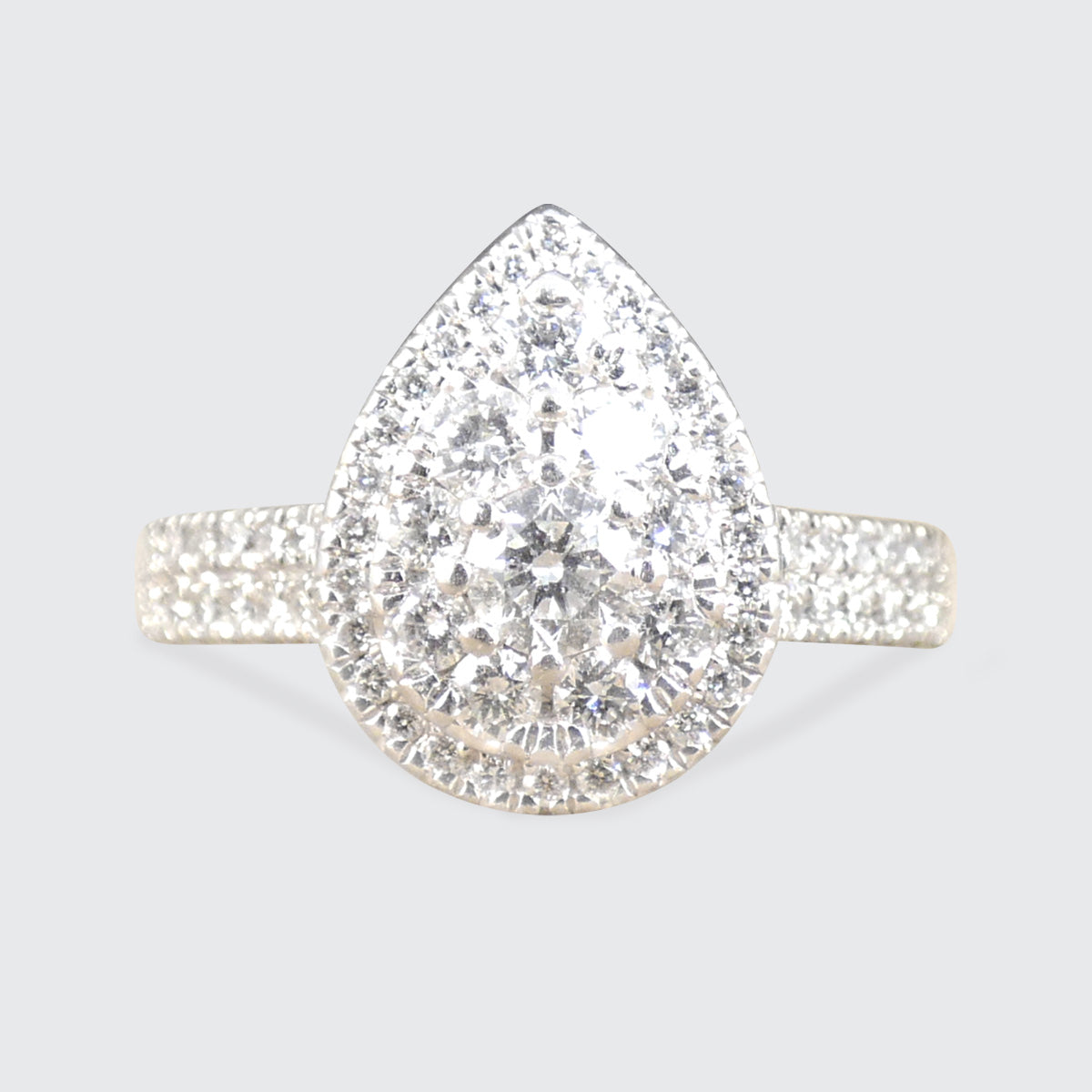 Diamond ring with pear-shaped center stone on a light gray background
