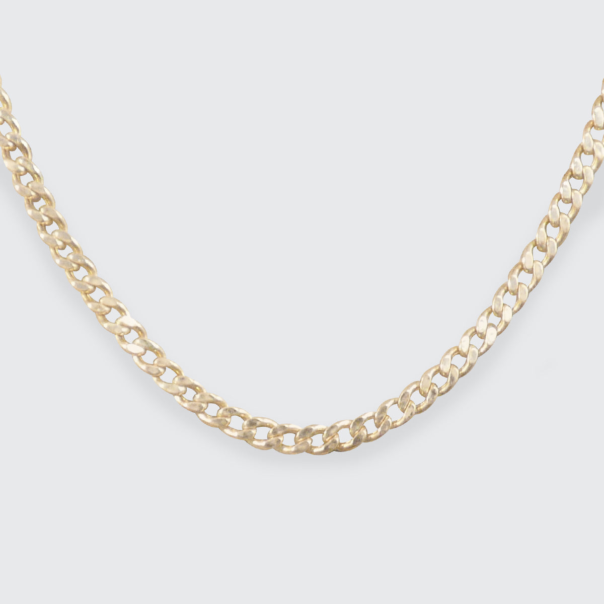 A flat curb chain in yellow gold